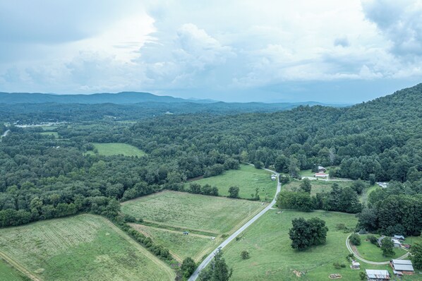 An aerial view of a rural landscape with fields, a winding road, and scattered buildings.