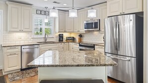 A modern kitchen with white cabinetry, stainless steel appliances, granite countertops, and pendant lighting. - Private Pool, 2 Blocks to Beach--Perfect Family Getaway! (Isle of Palms)
