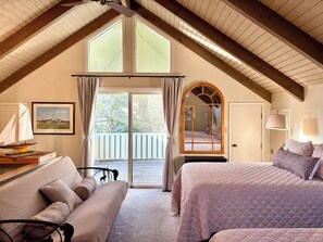 A bedroom with a large window, a bed, a sofa, and a mirror.
