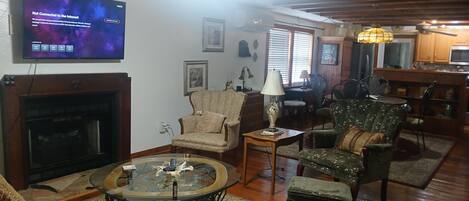 A living room with a fireplace, a television displaying a 'Not Connected to the Internet' message, and a dining area with wooden cabinets and a chandelier.