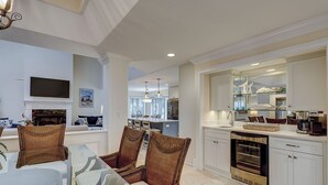 A modern kitchen with white cabinetry, a built-in oven, and a dishwasher. There is a dining area with wicker chairs and a glass table. - 3rdRowOcean Palmetto Dunes Dog Friendly Home w/ FREE Pool/Spa Heat Seasonally (Hilton Head Island)