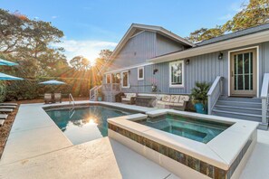 Ein Haus mit Pool, Gartenmöbeln und einer überdachten Terrasse.