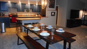 Een moderne keuken met donkere kastjes, een rode oven, en een eethoek met houten tafels en banken.