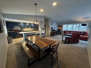 Una cocina moderna con armarios azul oscuro, una mesa de comedor de madera con bancos y un sofá rojo en la sala de estar.