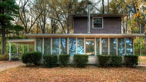 A modern house with large windows and a covered porch.