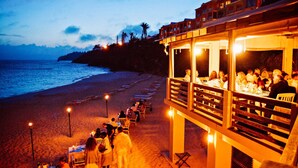 Un restaurante en la playa con terraza al aire libre y vistas al océano.