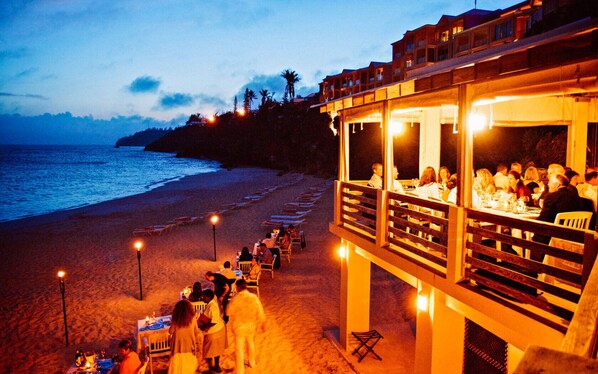 A beachfront restaurant with outdoor seating overlooking the ocean.