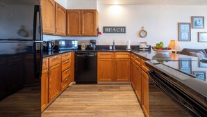 A modern kitchen with wooden cabinets, a black refrigerator, and a dishwasher. - Sands Lookout at Nye Beach - Beach front,Easy access condo with great ocean view (Newport)