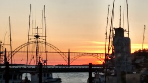 A sunset over a bridge with boats docked at a marina. - Sands Lookout at Nye Beach - Beach front,Easy access condo with great ocean view (Newport)