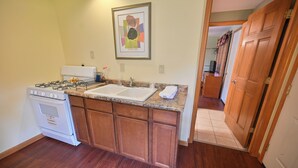 Una cocina con estufa, pileta y muebles de madera.