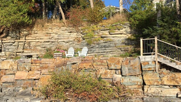 Una escalera de piedra que sube una colina, con sillas Adirondack blancas en la cima.