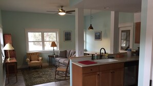 Una cocina moderna con armarios de madera, una isla central y un comedor con sofá y lámpara.