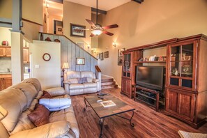 A living room with a leather sofa, a coffee table, a TV, and a wooden cabinet.