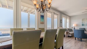 A dining area with a view of the ocean, a chandelier, and a beach-themed wall art. - BEACH FRONT!  The Happy Mullet: Surf, Sun, the Perfect House and Ms. Pac Man (Galveston)