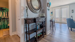 A room with a wooden console table, a mirror, and a blue chair. - BEACH FRONT!  The Happy Mullet: Surf, Sun, the Perfect House and Ms. Pac Man (Galveston)
