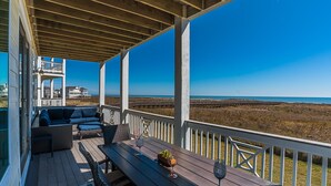 A wooden deck with outdoor seating and a view of the beach. - BEACH FRONT!  The Happy Mullet: Surf, Sun, the Perfect House and Ms. Pac Man (Galveston)