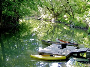 Guests can enjoy serene views of the river from the dock, surrounded by lush greenery and moored boats.