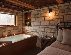 Relax in a cozy cabin-like bathroom with a bathtub and rustic stone walls.