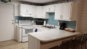 A kitchen with white cabinets, a stove, a microwave, and a coffee maker. - Paradise found -  close to everything and endless beautiful beach access (FT Walton beach)