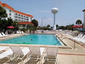 Una piscina con sillones de descanso y una fuente alta.