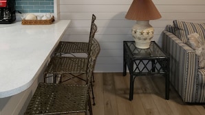 A kitchen with white cabinets, a coffee maker, and a wicker chair. There is a small table with a lamp and a striped sofa. - Paradise found -  close to everything and endless beautiful beach access (FT Walton beach)