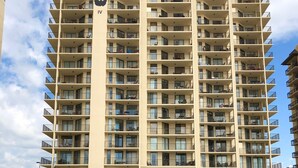 A multi-story hotel with balconies, a beach view, and an emergency phone. - 7th Fl. Ocean Front Balcony💎So Clean, WIFI, Pools, Athletic Courts, Grills.. (Orange Beach)