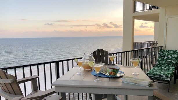 A balcony with a table set for two, overlooking the sea. - 7th Fl. Ocean Front Balcony💎So Clean, WIFI, Pools, Athletic Courts, Grills.. (Orange Beach)