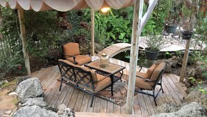 Une terrasse en bois avec une table et des chaises, entourée de rochers et de plantes.