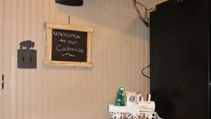 A kitchen with a wooden table, two stools, a chalkboard sign, a television, and a decorative Christmas tree.