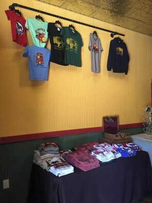 Una habitación con una mesa que exhibe diferentes prendas de vestir y una pared con ropa colgada.