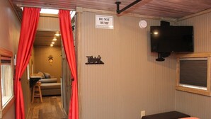 A room with a bed, a television, a sign that says 'DO NOT HUMP,' and a small table with a chair.
