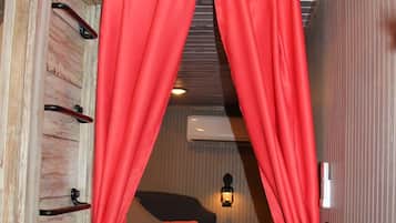 Une chambre à coucher avec un lit, une fenêtre avec des rideaux, un climatiseur fixé au mur et une pancarte au-dessus de la fenêtre.