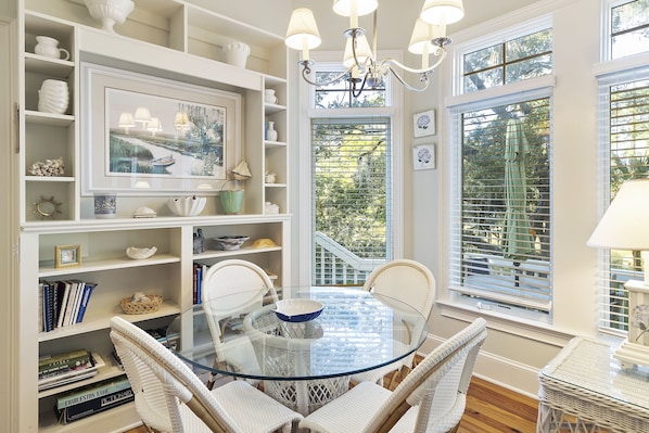 Cozy space with a round dining table, wicker chairs, and a chandelier.