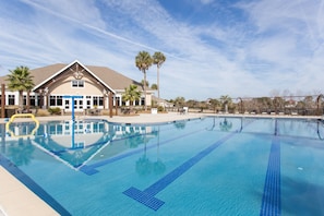 Swimmers can enjoy a refreshing dip in the large pool surrounded by lush palm trees.