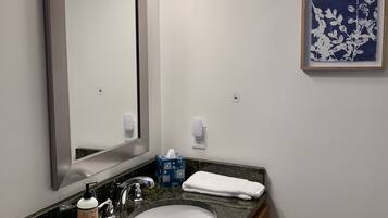 A bathroom with a large mirror, a sink, a towel, and a framed picture on the wall.