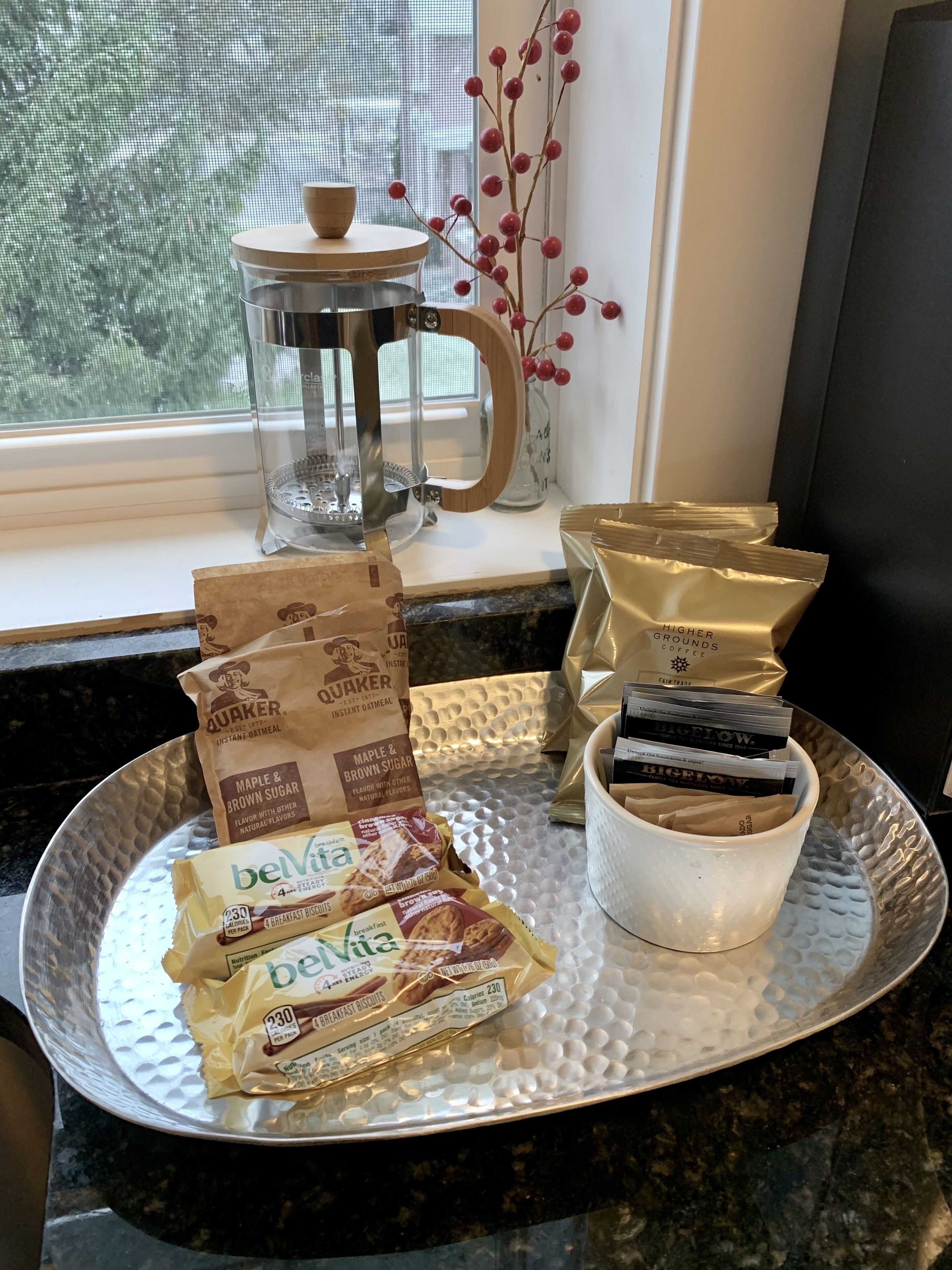A kitchen counter with a tray holding breakfast items, a coffee maker, and a decorative vase.