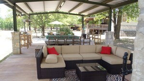 En udendørs patio med en modulsofa, en rød lænestol og en måtte med zebraprint.