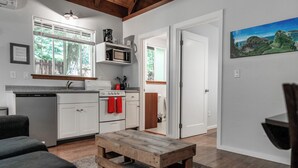 Une cuisine moderne avec des meubles blancs, un banc en bois et un coin repas avec une table.