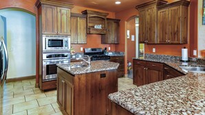 A kitchen with wooden cabinets, granite countertops, stainless steel appliances, and a built-in island. - 5 Bedrooms with Heated Private Pool, Last minute rates are posted! (Saint George/Washington)
