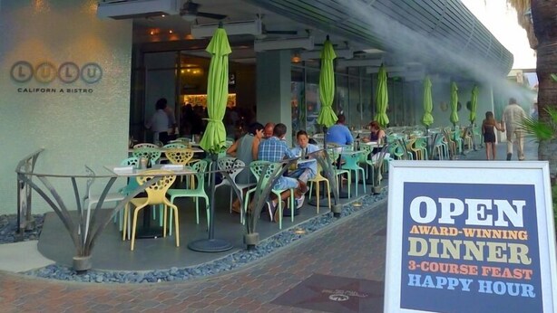 An outdoor dining area with tables and chairs, a sign advertising an award-winning dinner, and the restaurant's name, Lulu California Bistro. - 4 Bedroom plus den/office 3 Bath Private House W/Pool & Hot Tub in Palm Spring (Palm Springs)