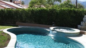 A swimming pool with a hot tub, surrounded by a hedge and a tiled roof in the background. - 4 Bedroom plus den/office 3 Bath Private House W/Pool & Hot Tub in Palm Spring (Palm Springs)