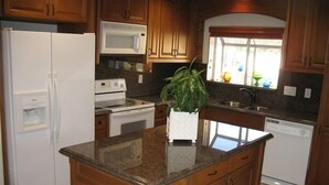 A kitchen with wooden cabinets, a white refrigerator, a microwave, a stove, a sink, and a dishwasher. - 4 Bedroom plus den/office 3 Bath Private House W/Pool & Hot Tub in Palm Spring (Palm Springs)