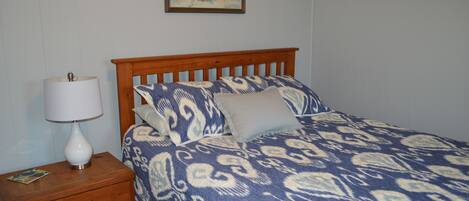 A bedroom with a wooden bed, a nightstand with a lamp, and a painting on the wall.