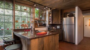 A kitchen with a wooden island, stainless steel appliances, and a view through large windows.