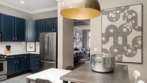 Una cocina moderna con armarios azul marino, electrodomésticos de acero inoxidable y una lámpara colgante grande.