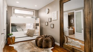 Un dormitorio con una cama litera, un espejo grande y un tapiz de cuero de vaca.