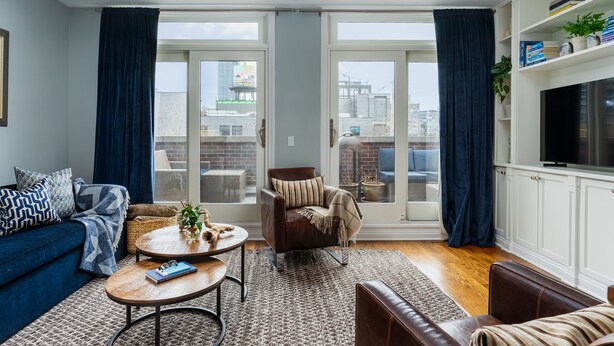 Una sala de estar con sofá, sillón, mesa de centro y mueble para televisión.
