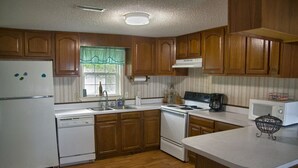 Una cocina con armarios de madera, un refrigerador blanco, una estufa, un fregadero y un microondas.