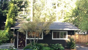A residential house with a dark exterior, a white door, and a small garden with various plants and a tree. - the Beach Suite on Lemolo!    CLEAN & PRIVATE ... getaway & relax. (Poulsbo)