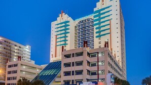 A hotel with a modern design, featuring a prominent glass facade and a rooftop pool. - Oceanfront Gem Clean 1080sf New Furniture, Beds, Carpet Free WiFi Cable Gym Park (Myrtle Beach)